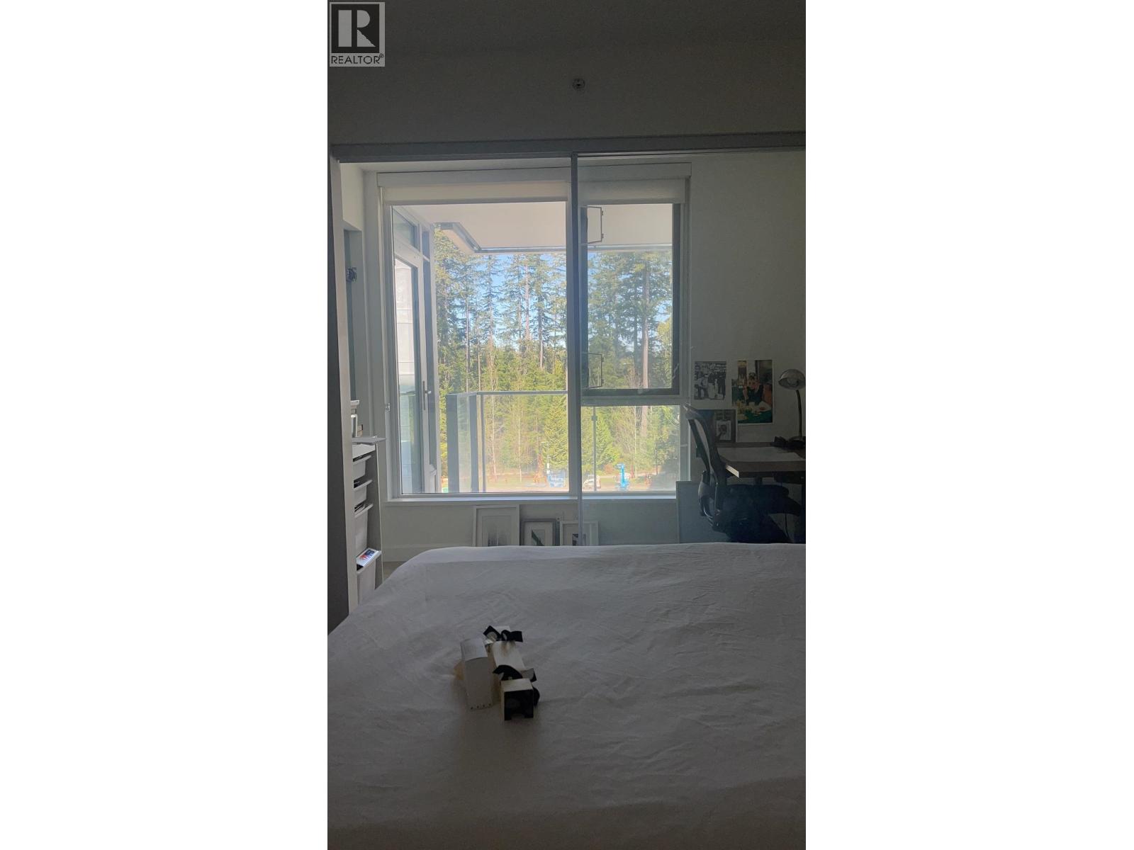 A bedroom with a bed and a window overlooking a forest.