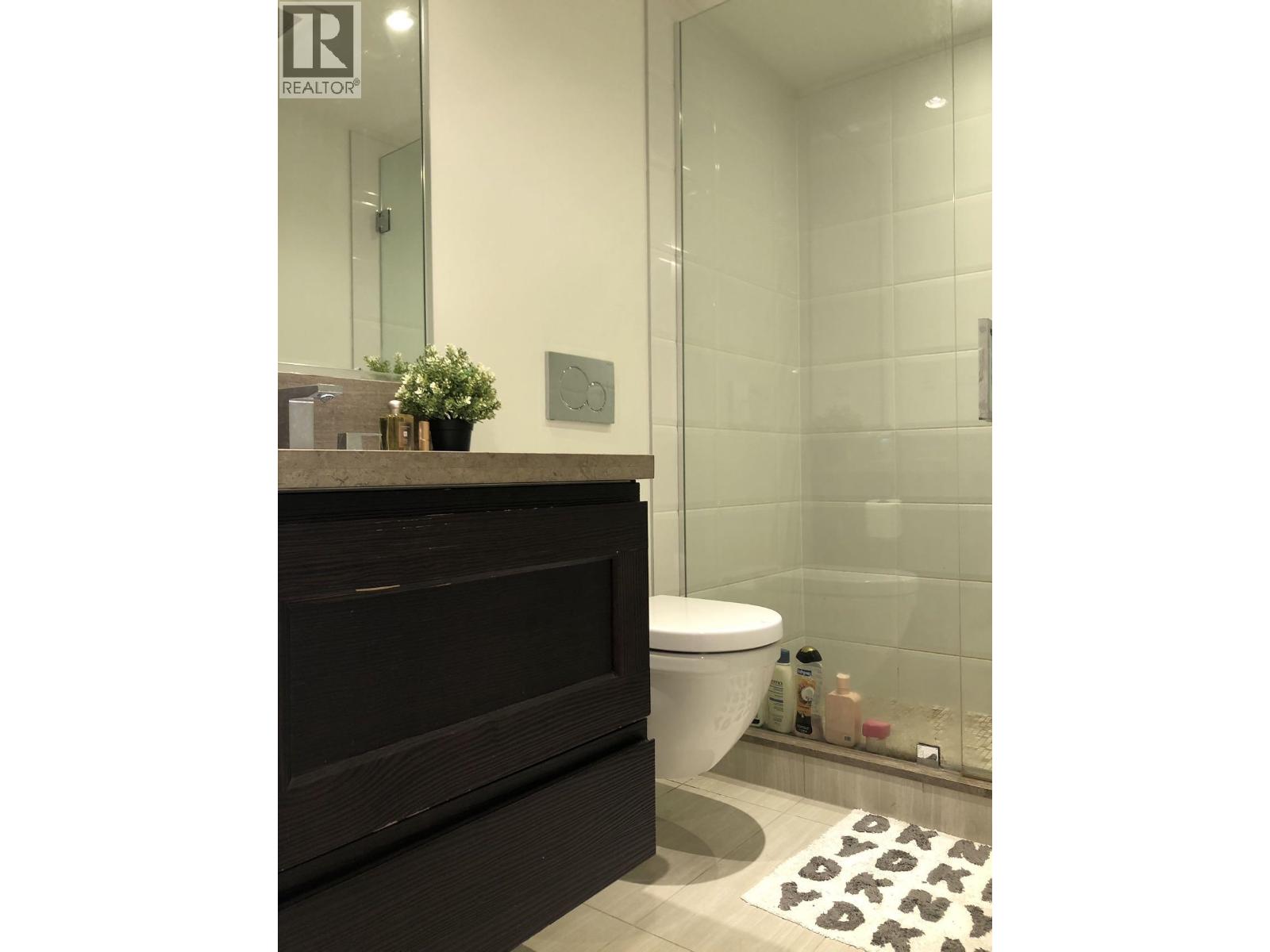 A bathroom with a toilet, a mirror, and a plant.