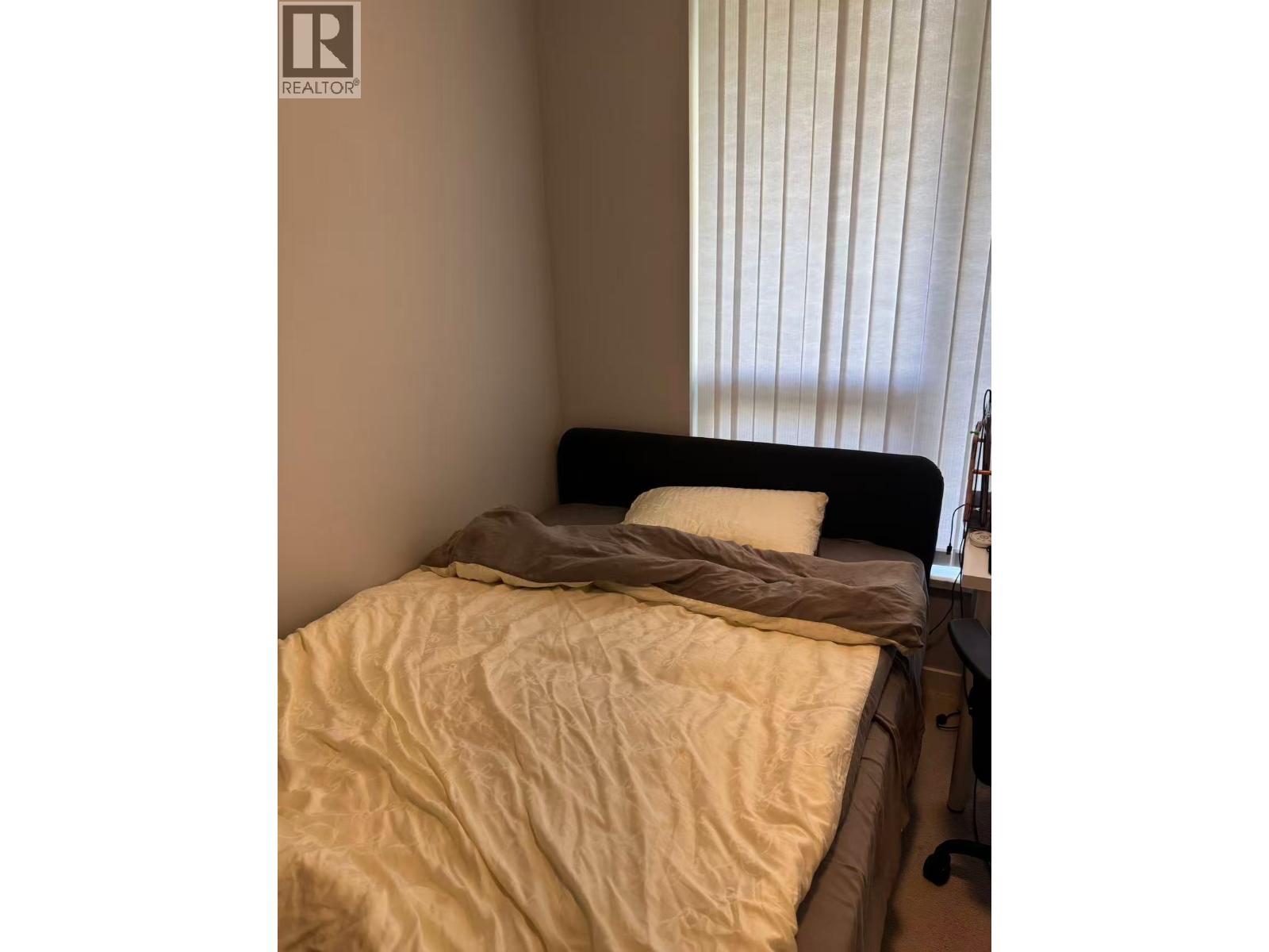 A bed with a black headboard and a white pillow is in a room.