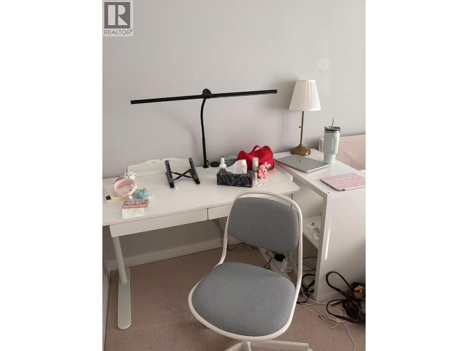 A white desk with a grey chair and a laptop on it.