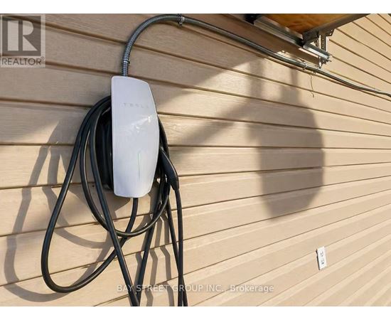 A white Tesla Powerwall is mounted on a house wall.