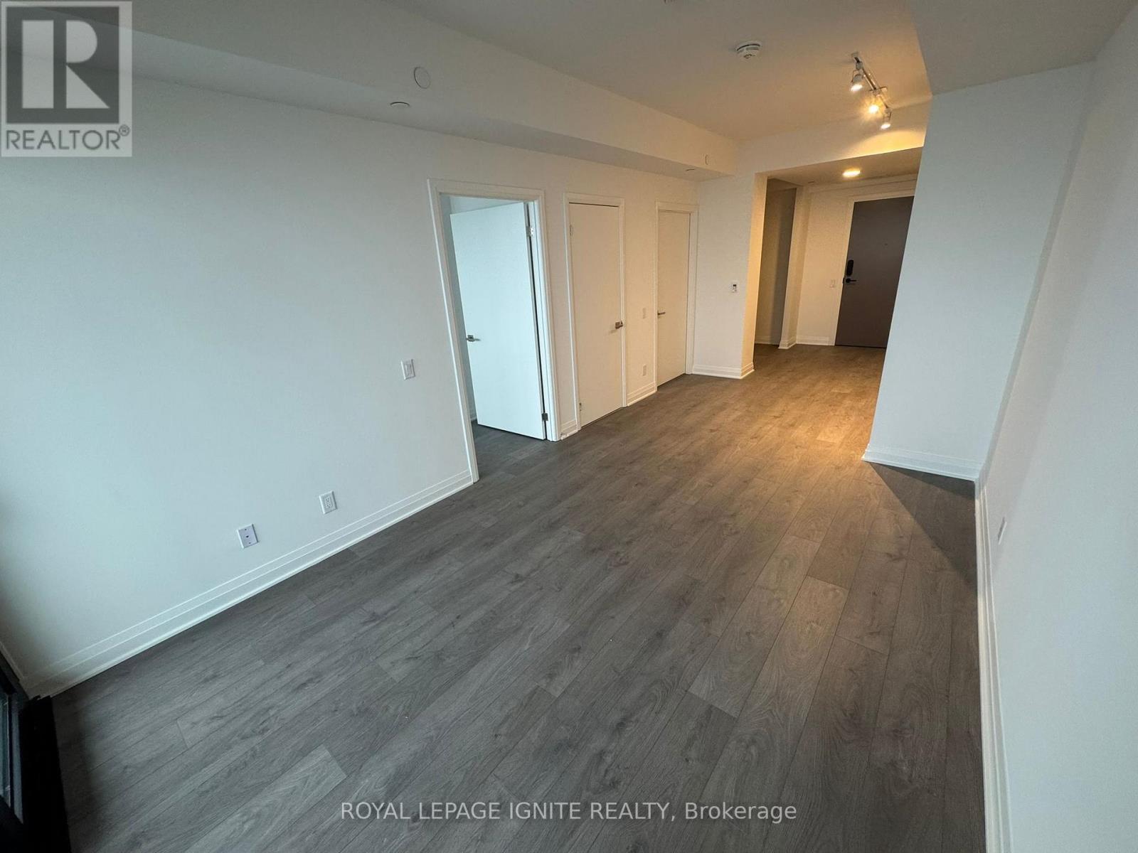 A spacious room with wooden flooring and white walls.
