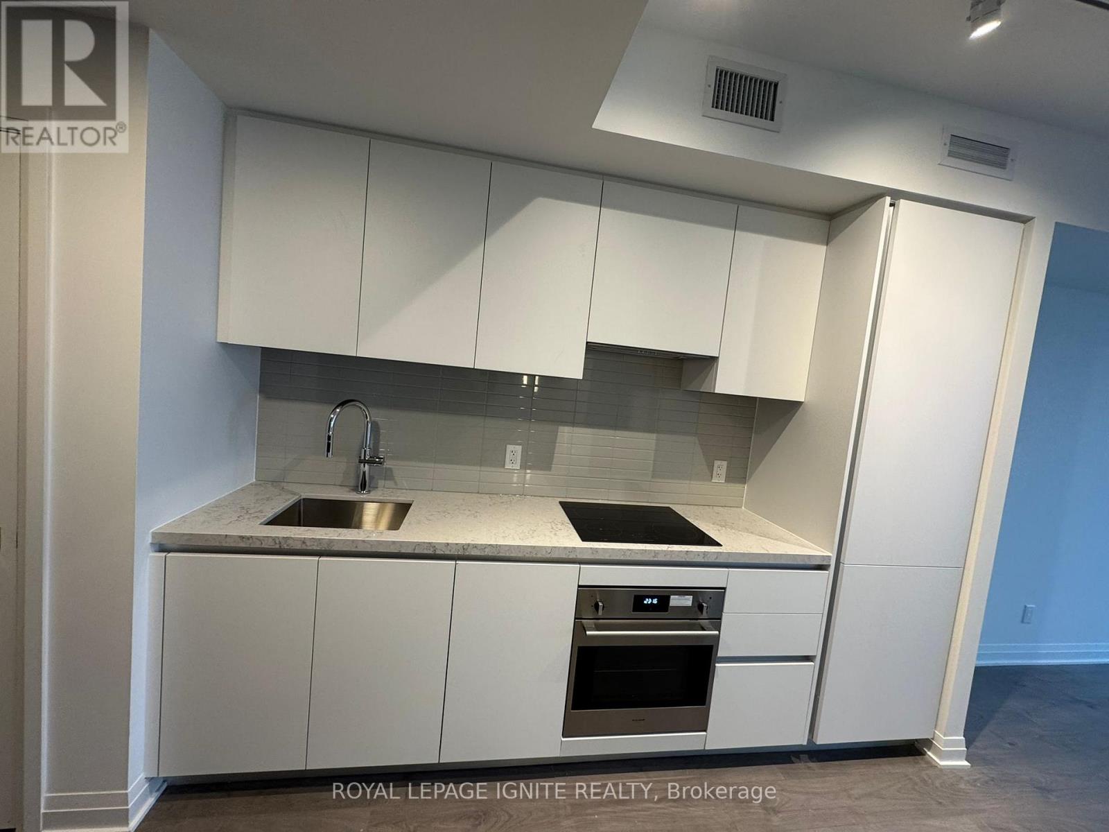 A modern kitchen with white cabinets and stainless steel appliances.
