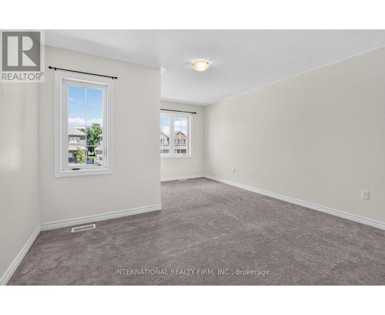 A room with a carpeted floor and a window showing a view of buildings outside.