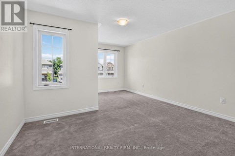 A room with a carpeted floor and a window showing a view of buildings outside.