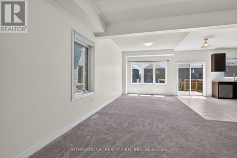 A spacious room with a carpeted floor and a large window.