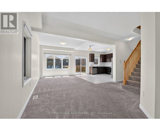 A spacious living room with a staircase leading to the upper floor.