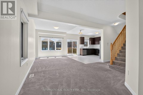 A spacious living room with a staircase leading to the upper floor.