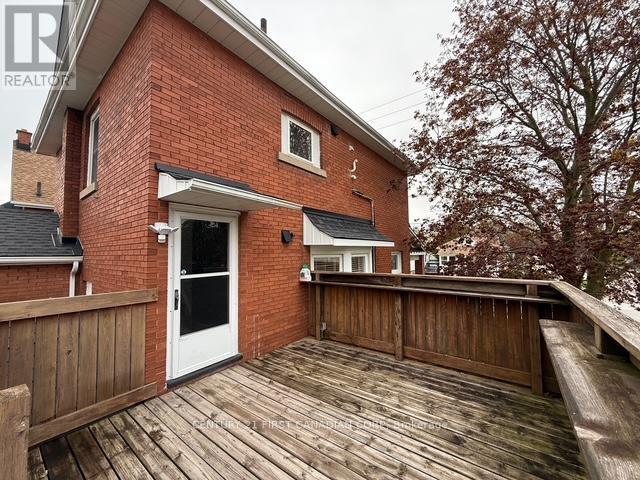 A red brick house with a white door and a wooden deck.