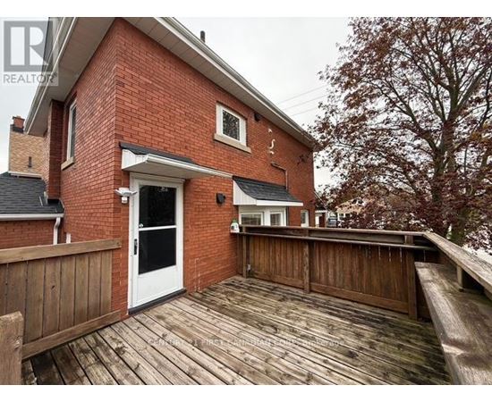 A red brick house with a white door and a wooden deck.