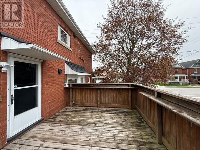 A wooden deck with a white door and a tree in the background.