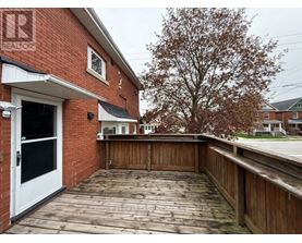 A wooden deck with a white door and a tree in the background.