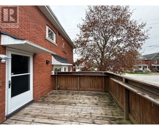 A wooden deck with a white door and a tree in the background.