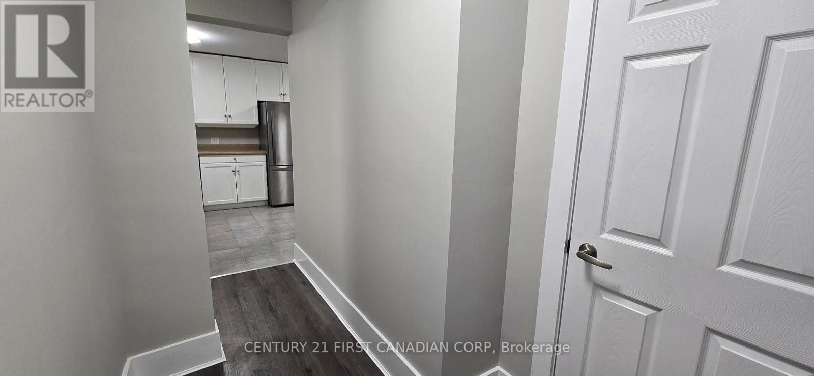 A hallway with a door on the right and a kitchen in the background.