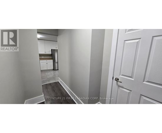 A hallway with a door on the right and a kitchen in the background.