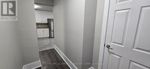 A hallway with a door on the right and a kitchen in the background.