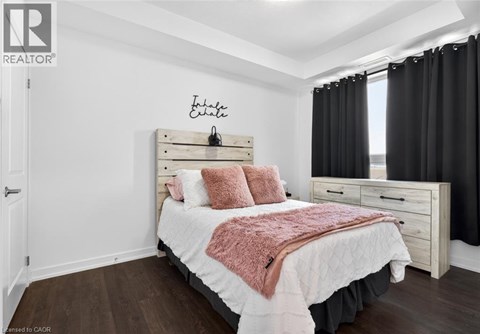 A bedroom with a bed, nightstand, and a wall hanging with the word "Estate" on it.