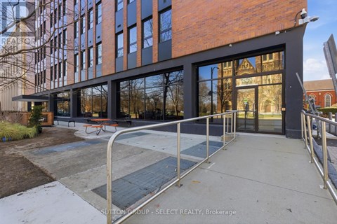 A modern building with a glass facade and a metal railing in front.