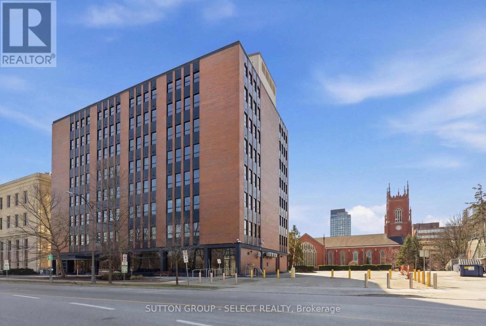A tall brick building with many windows is for sale.