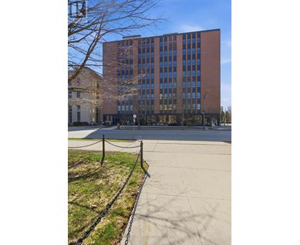 A tall brick building with a black fence in front.