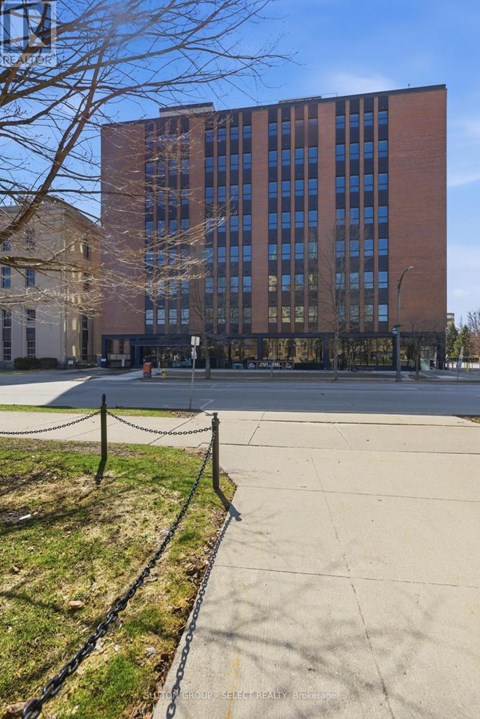 A tall brick building with a black fence in front.