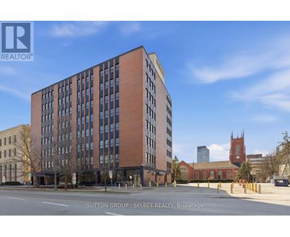 A tall brick building with many windows is for sale.
