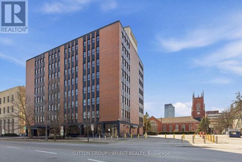 A tall brick building with many windows is for sale.