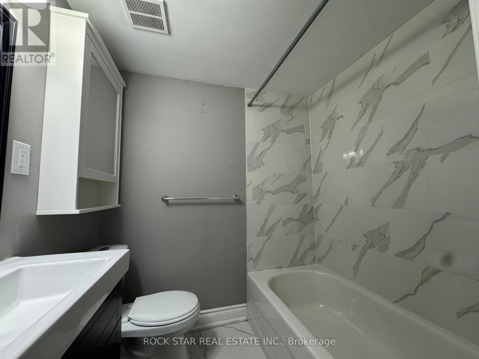 A bathroom with a marble wall and a white toilet.