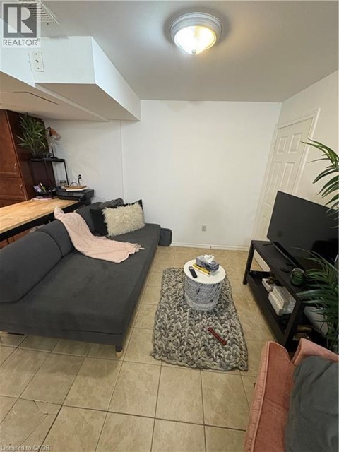 A living room with a grey couch and a black television.
