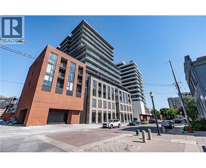 A modern building with a red brick facade is in the foreground with a glass building in the background.