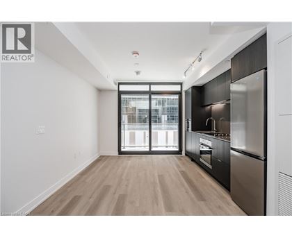 A modern kitchen with a stainless steel refrigerator and wooden flooring.