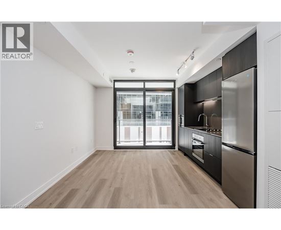 A modern kitchen with a stainless steel refrigerator and wooden flooring.