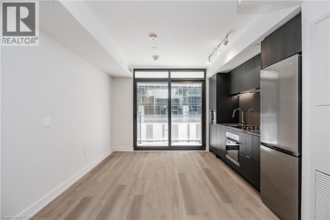 A modern kitchen with a stainless steel refrigerator and wooden flooring.