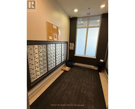 A hallway with a carpeted floor and mailboxes on the wall.
