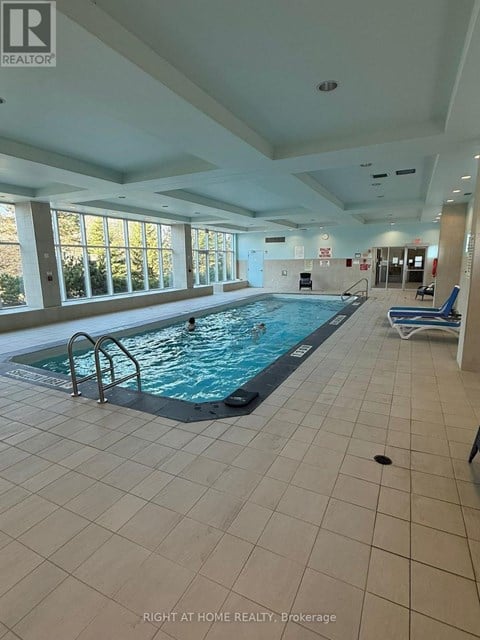 A large indoor swimming pool with a sunny view outside.