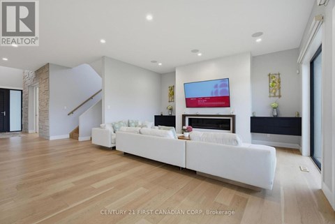 A modern living room with a white sofa and a flat screen TV mounted on the wall.