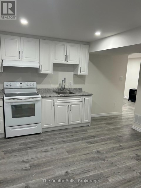 A kitchen with white cabinets and a stove top oven.