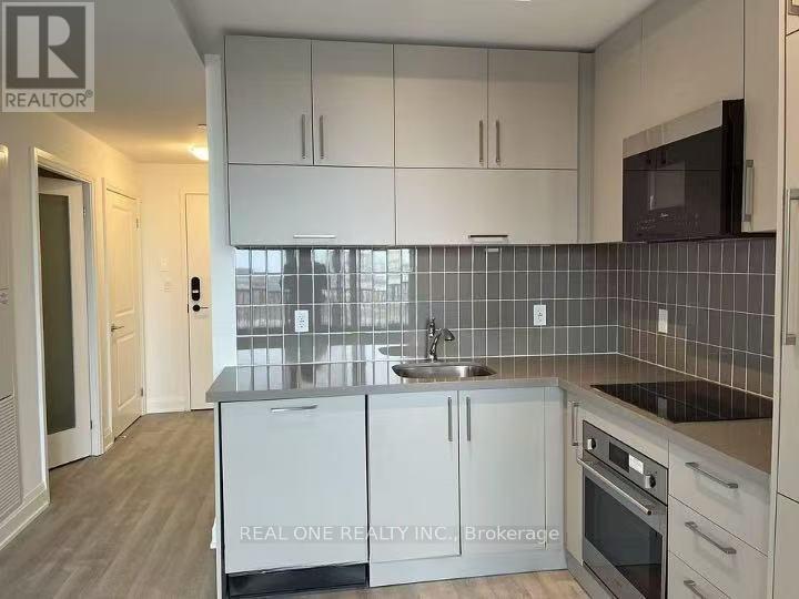 A kitchen with white cabinets and a black fridge.