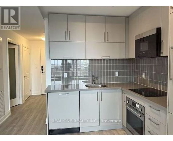 A kitchen with white cabinets and a black fridge.