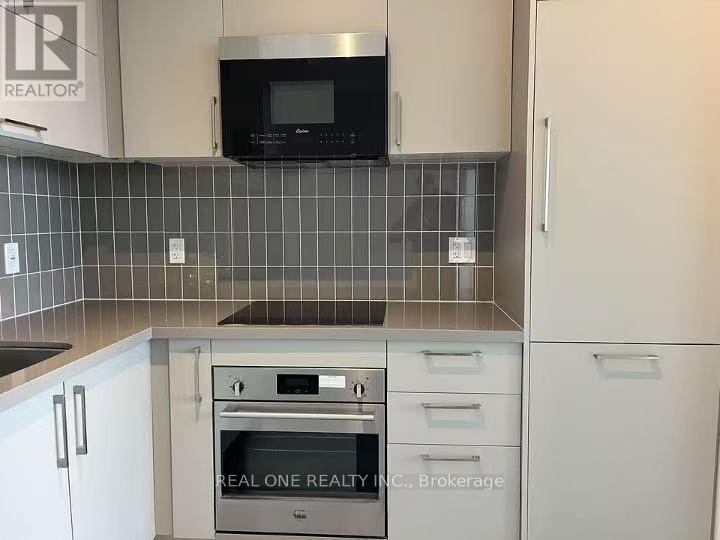 A kitchen with a microwave above the stove and a brokerage sign on the wall.
