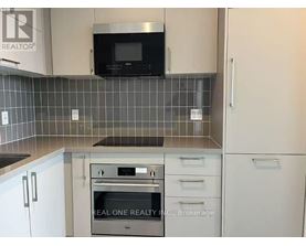 A kitchen with a microwave above the stove and a brokerage sign on the wall.