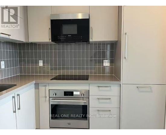 A kitchen with a microwave above the stove and a brokerage sign on the wall.