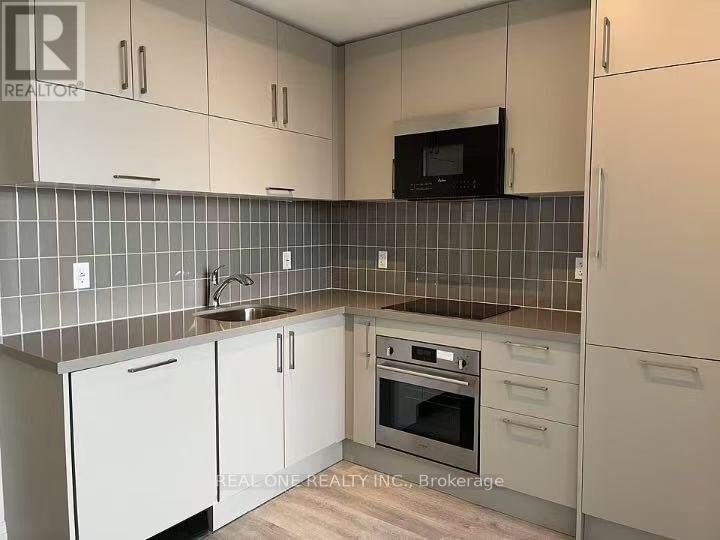 A kitchen with white cabinets and a black microwave above the stove.