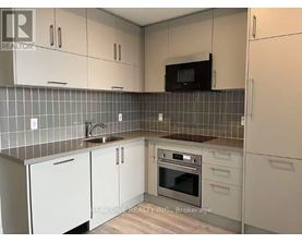 A kitchen with white cabinets and a black microwave above the stove.