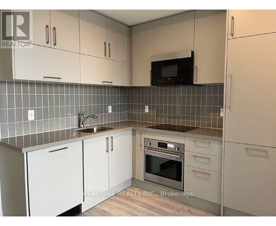 A kitchen with white cabinets and a black microwave above the stove.