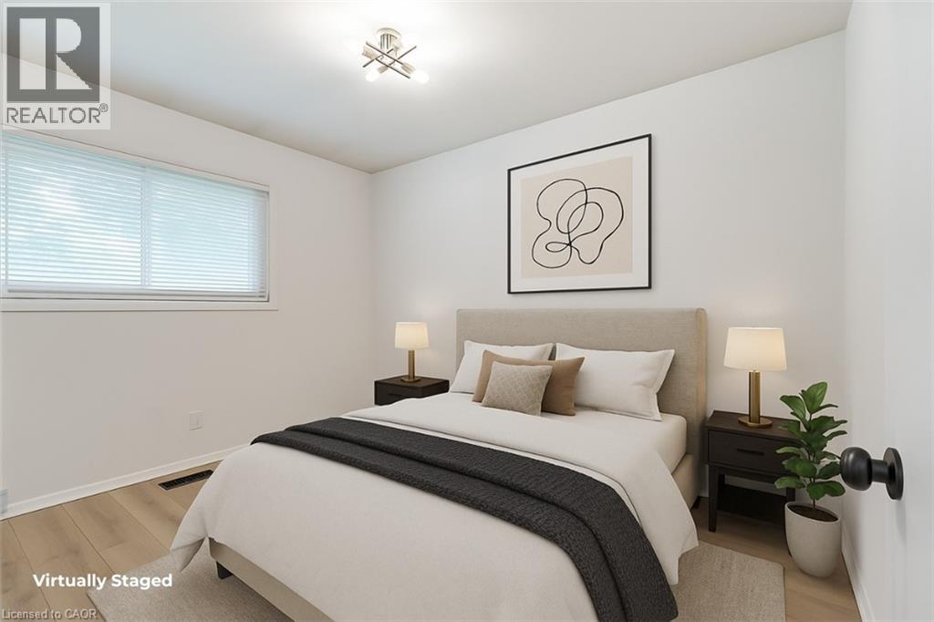 A bedroom with a large bed, a nightstand with a lamp, and a framed picture on the wall.
