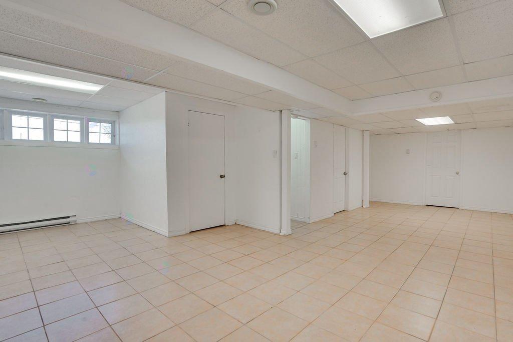 A spacious room with white walls and tiled flooring.