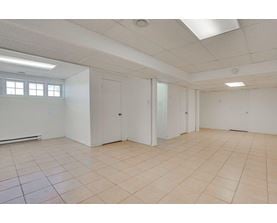 A spacious room with white walls and tiled flooring.