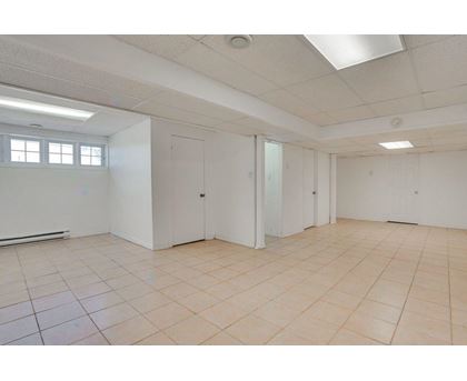 A spacious room with white walls and tiled flooring.
