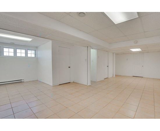 A spacious room with white walls and tiled flooring.